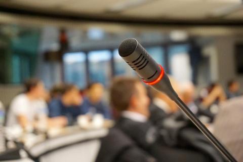 Image of a microphone with people sitting in the background.